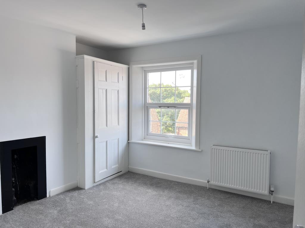 Lot: 145 - THREE-BEDROOM MAISONETTE - Bedroom with storage cupboard and decorative fireplace